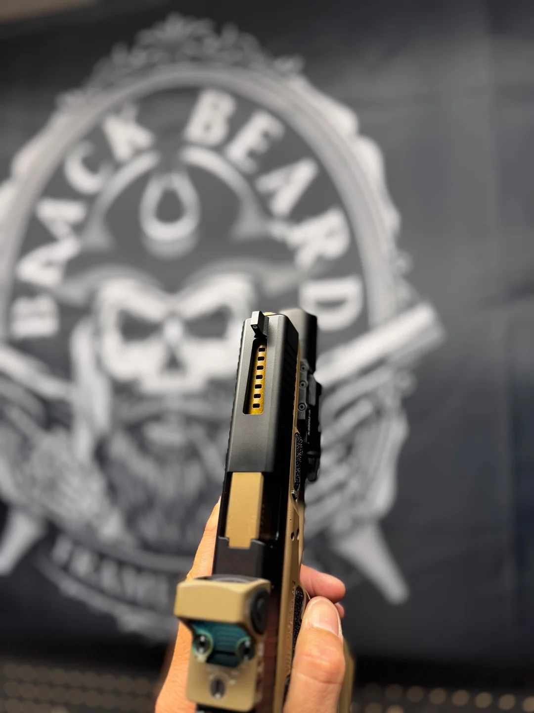 A ported slide with gold barrel held before the Black Beard Frameworks maker's mark